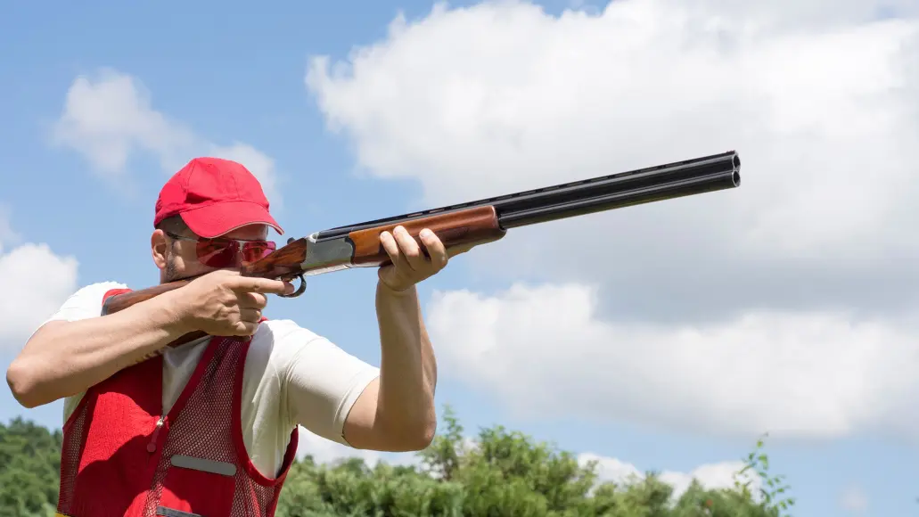 skeet shooter pointing shotgun