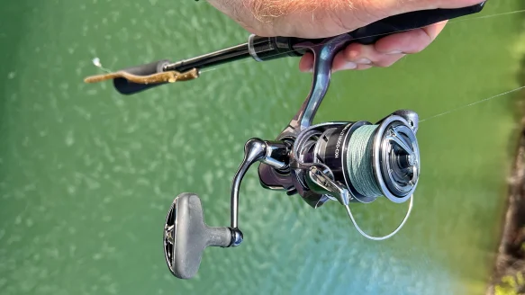 Hand holding fishing rod with spinning reel attached