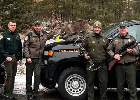 New Hampshire Fish & Game agents pose with a bobcat mount seized during "Operating Night Cat." 