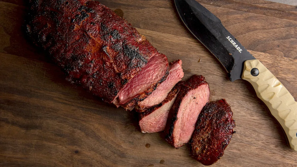 Smoked venison backstrap on a cutting board with a knife