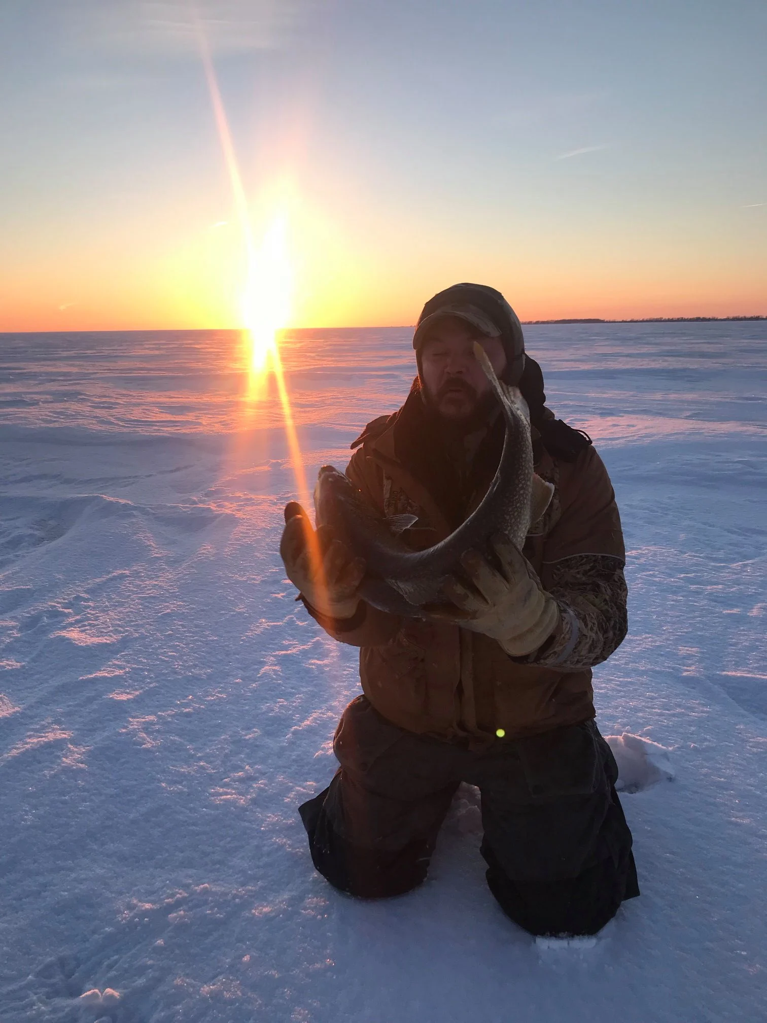 An ice fisherman poses with a trophy lake trout. 