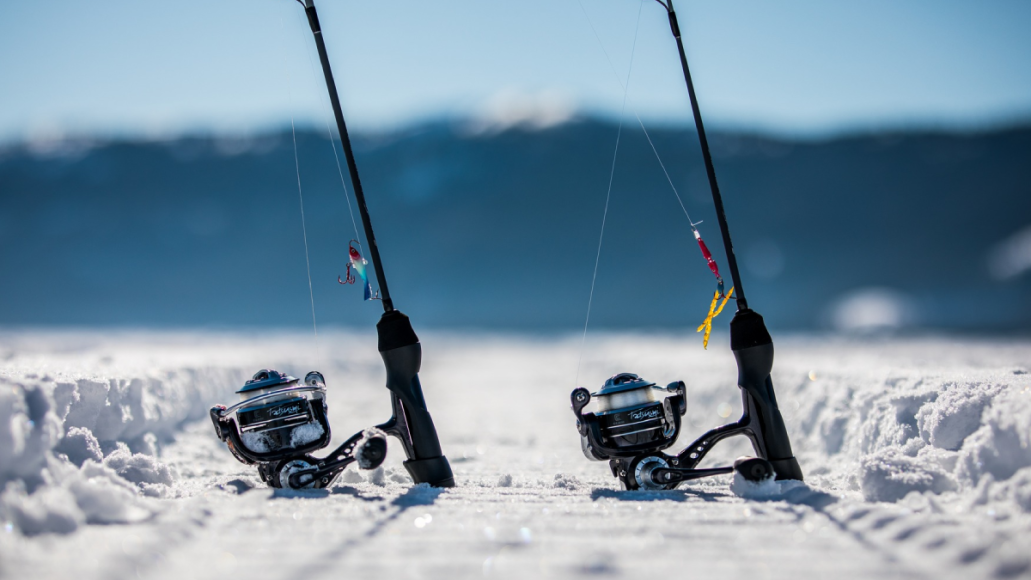 Clam ice fishing lures and reels sitting on frozen lake