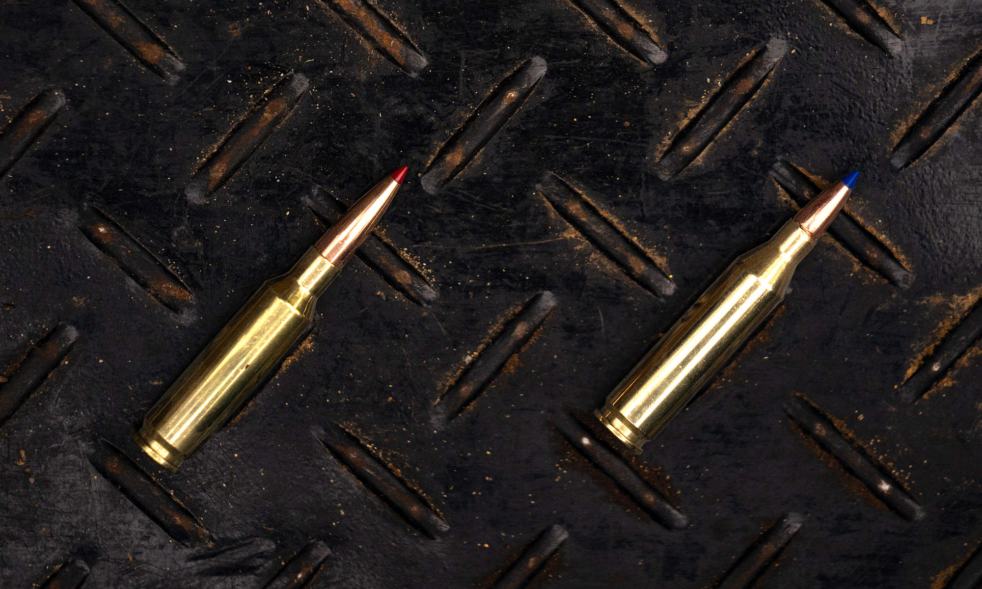 A 6.5 Creedmoor next to a 243 Winchester cartridge on a steel surface. 