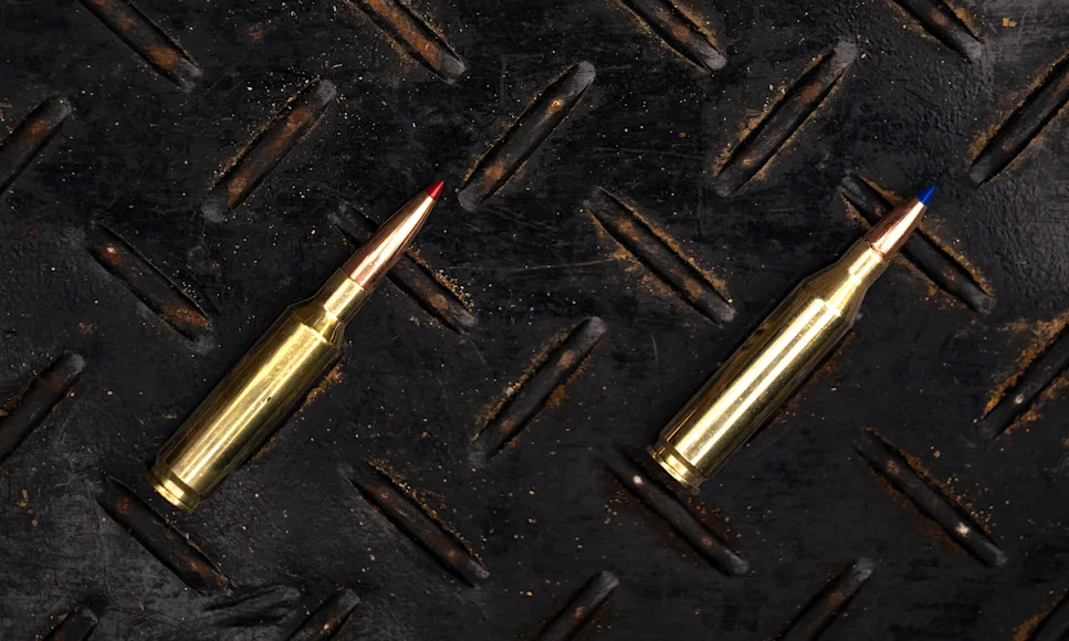 A 6.5 Creedmoor next to a 243 Winchester cartridge on a steel surface.