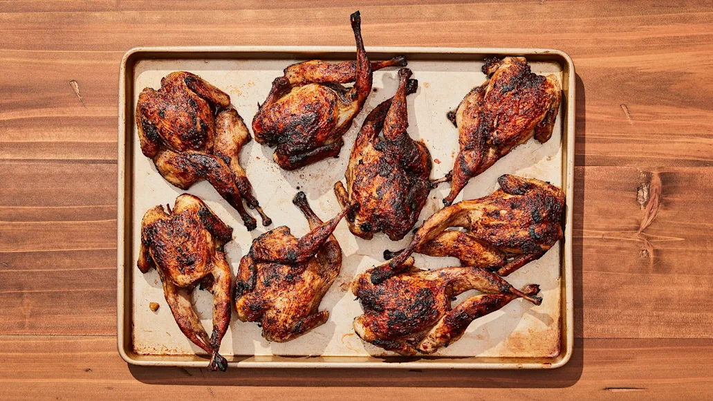 spatchcocked, cooked quail on metal tray and wood counter