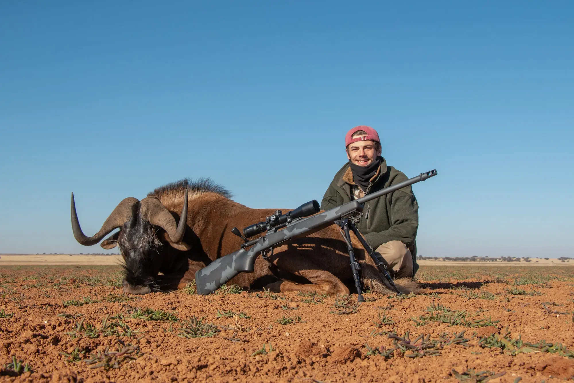 Hunter next to a dead wildebeast with a 6.5 Creedmoor.