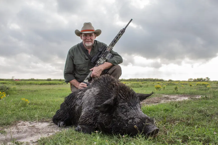 man standing next to dead wild pig