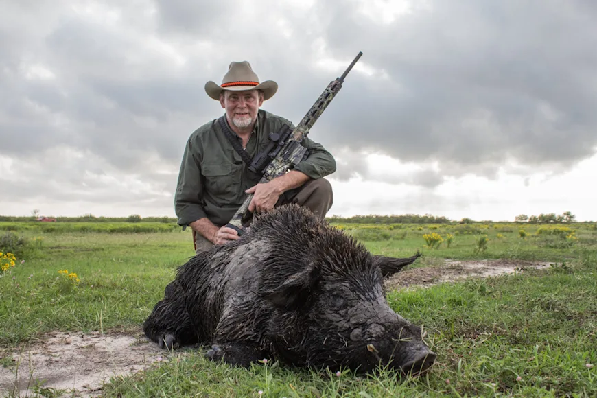 man standing next to dead wild pig