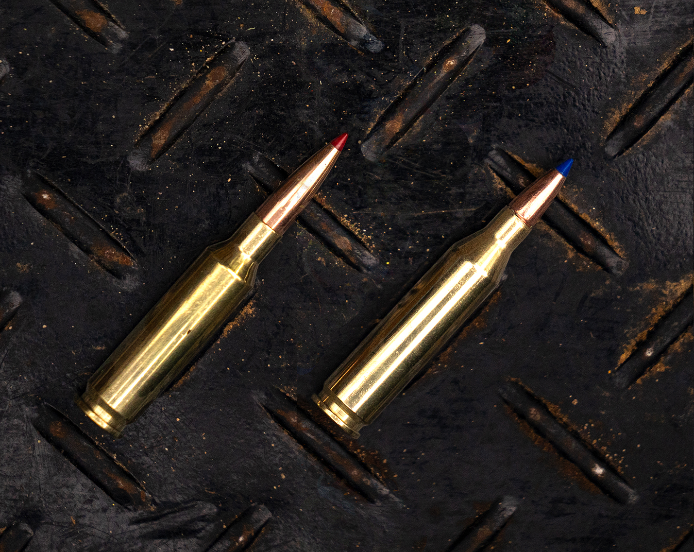 A 6.5 Creedmoor next to a 243 Winchester cartridge on a steel surface. 