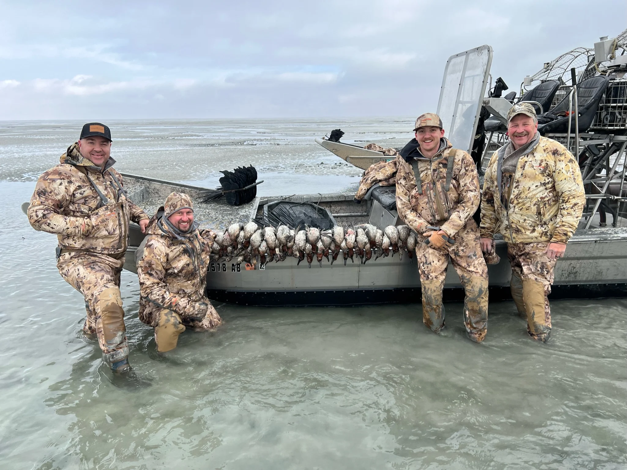 A group of hunters next to a pile of ducks 