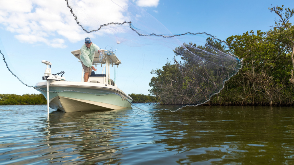 Angler throwing cast net off boat