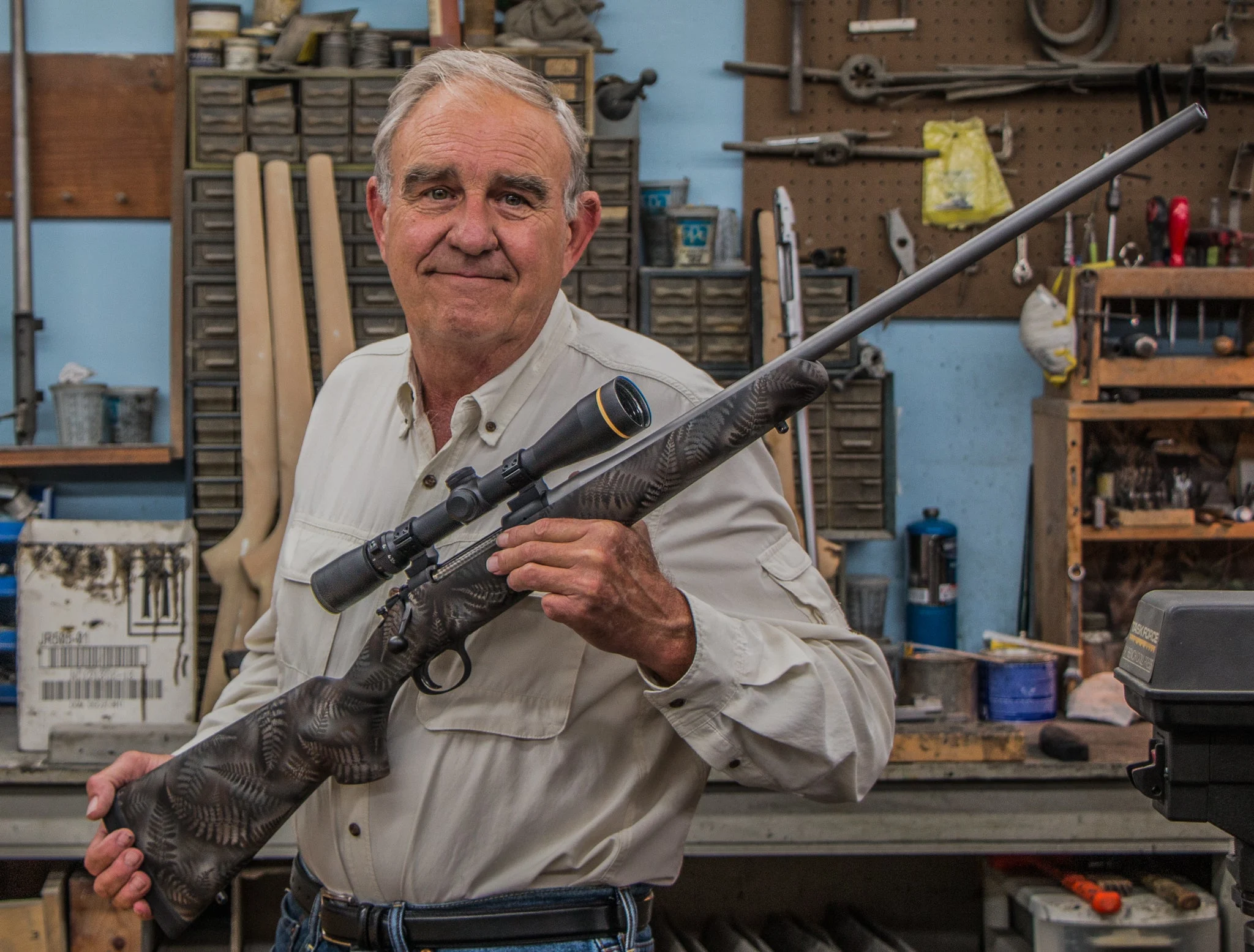 Riflemaker Melvin Forbes at his shop, holding up a New Ultralight Arms rifle.