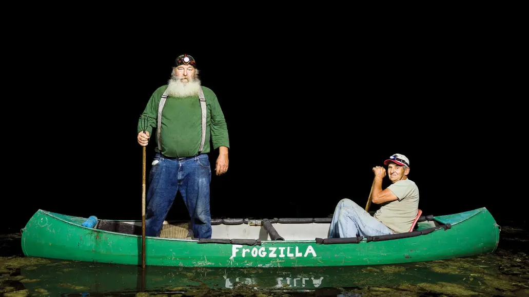 two men hunt frogs from their "frogzilla" canoe