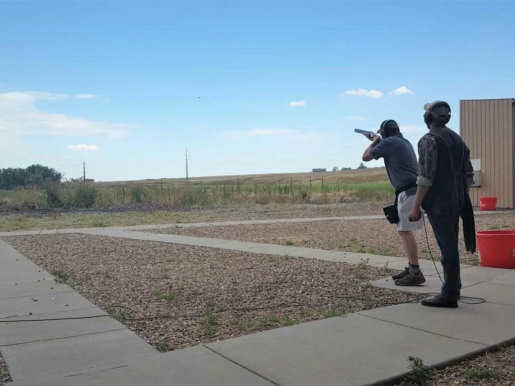 Two men trap shooting at a shooting range.