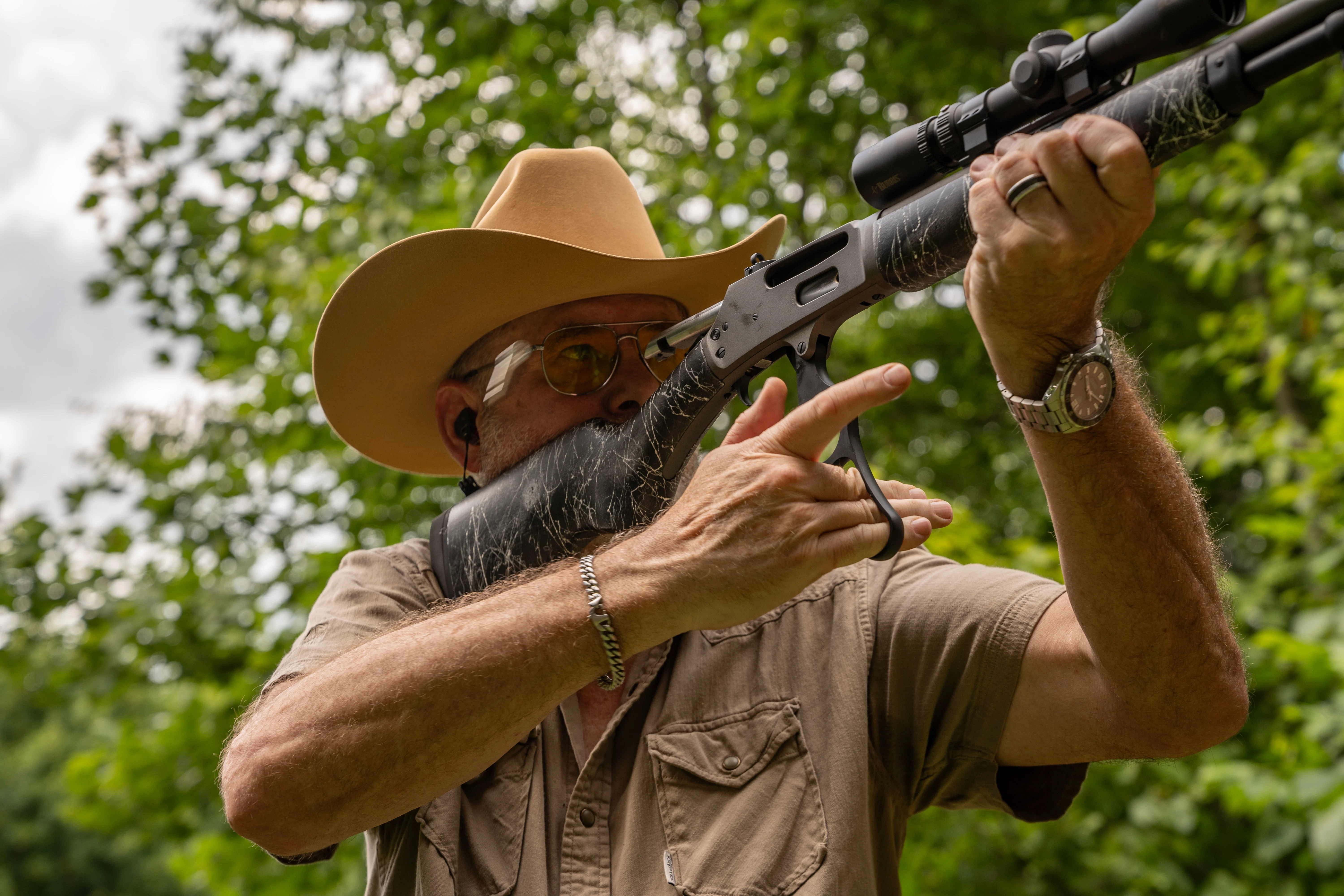 A shooter works the lever on a Dove Custom Appalachian Scout, with woods in the background.