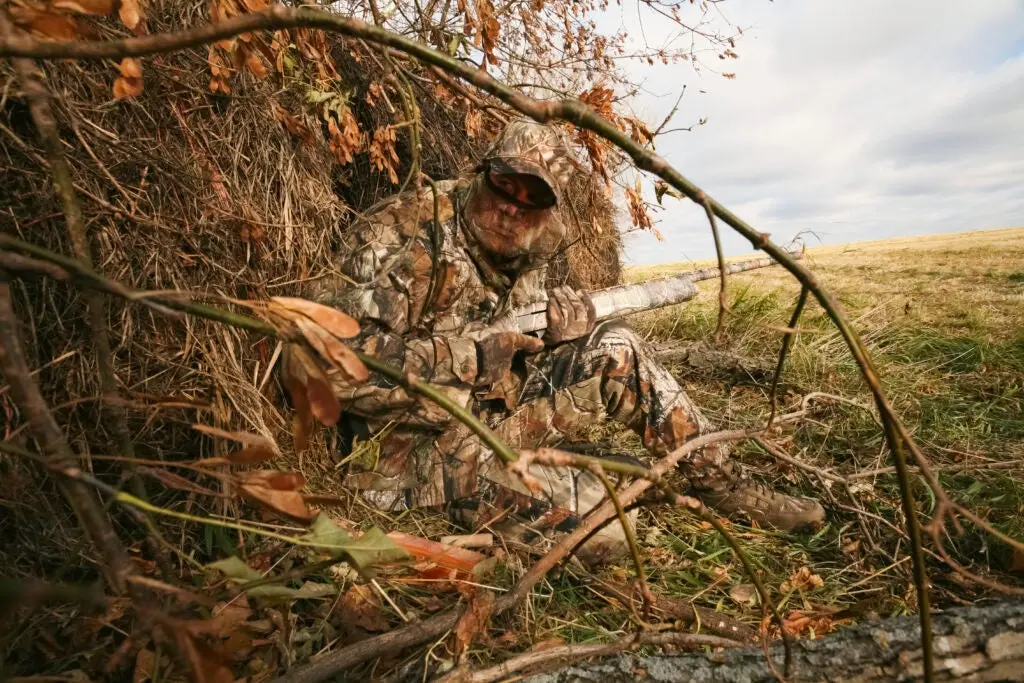 Turkey hunter sitting in the grass waiting for a bird.