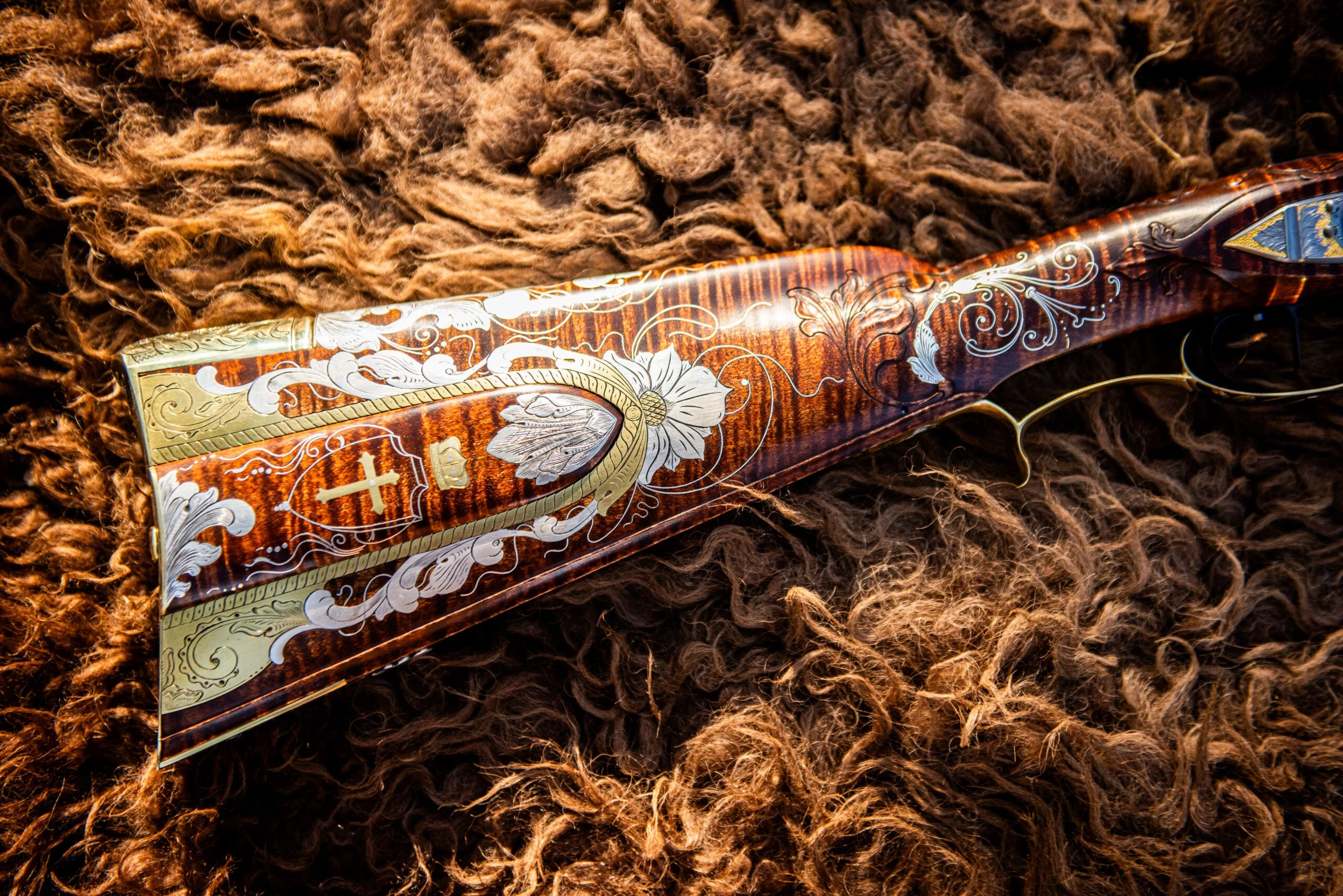 Ornately decorated butt stock of a flintlock rifle lying on a buffalo hide