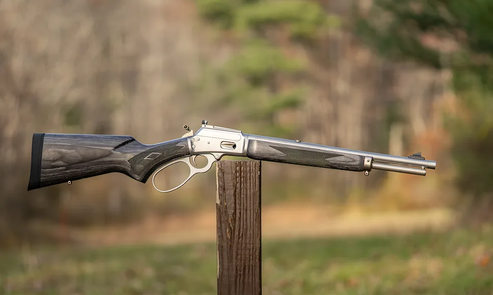 Marlin 1894 Trapper 10mm Automatic rifle balance on a post in a field.