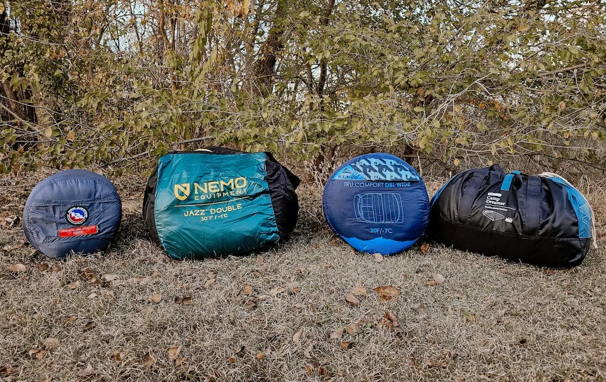 Four double sleeping bags for camping rolled up on grass