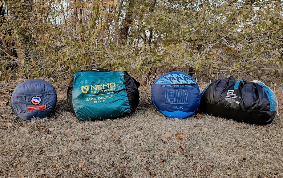 Four double sleeping bags for camping rolled up on grass