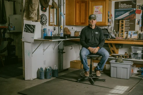 Josh Smith sits at a work bench in his Montana knife shop. 