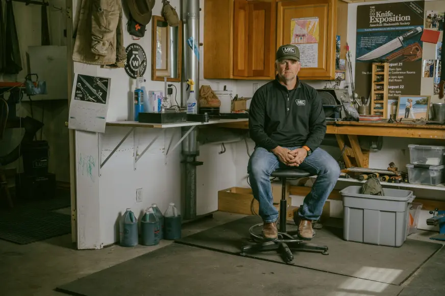 Josh Smith sits at a work bench in his Montana knife shop. 