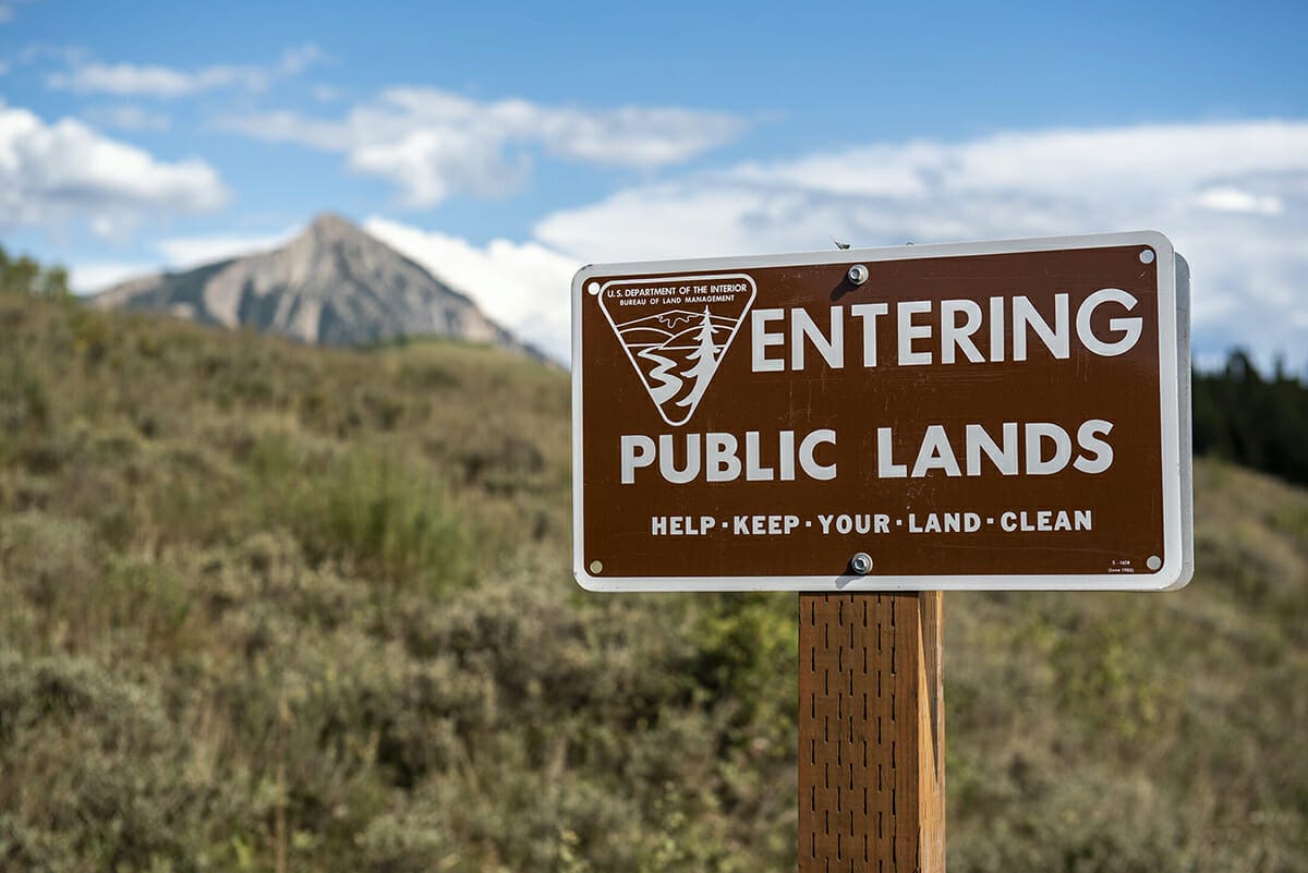 A Bureau of Land Management sign in front of a mountain backdrop. 