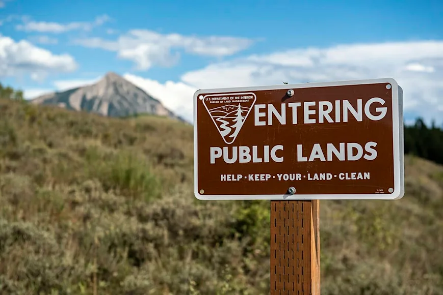 A Bureau of Land Management sign in front of a mountain backdrop.