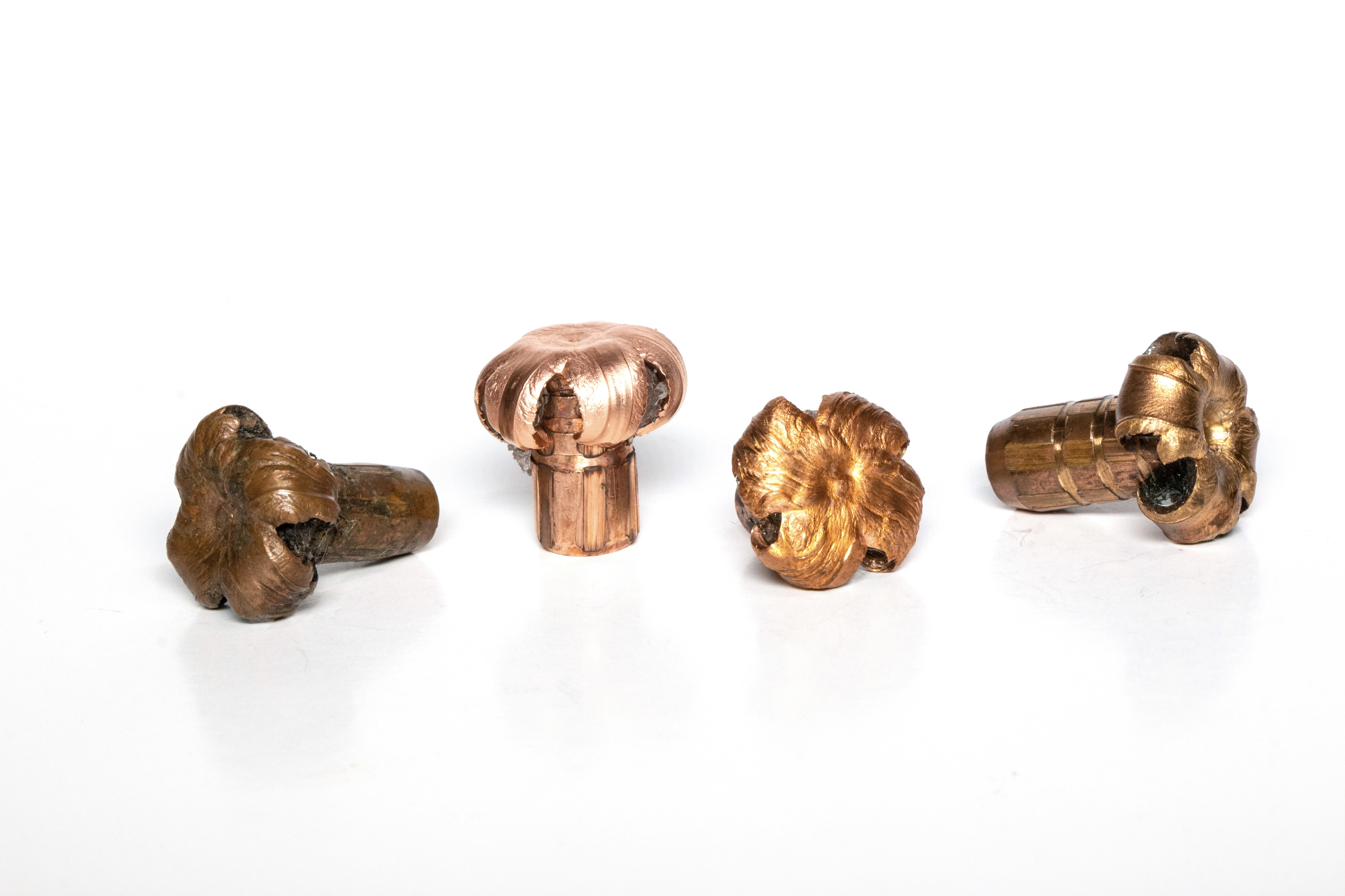 Four fired rifle bullets showing varying amounts of bullet-expansion, on a white background. 