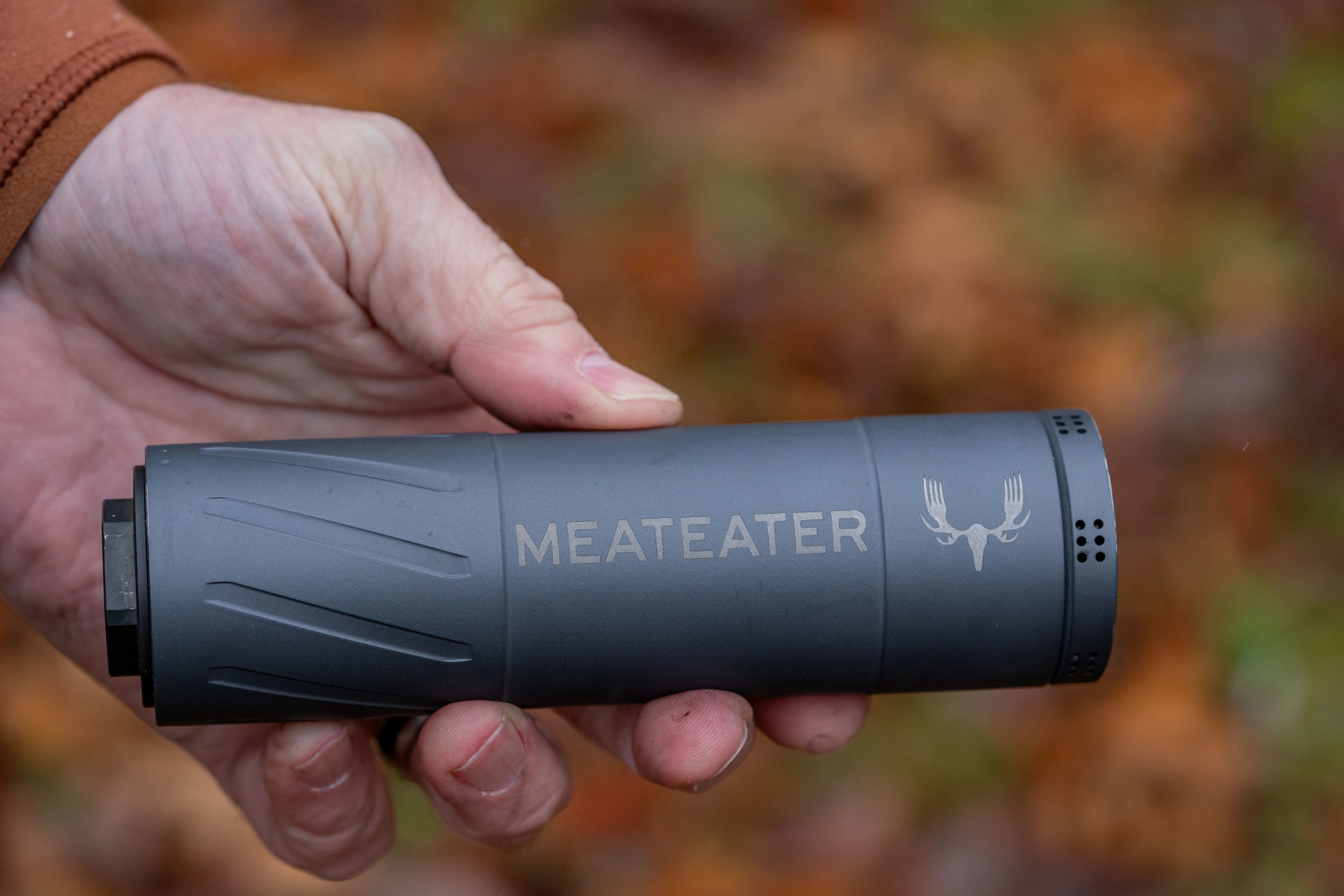 A shooter holds a rifle supressor. 