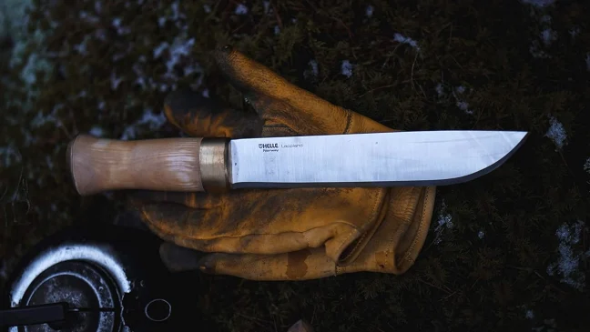 Helle Lappland camp knife resting on a pair of leather gloves near a camp kettle. 