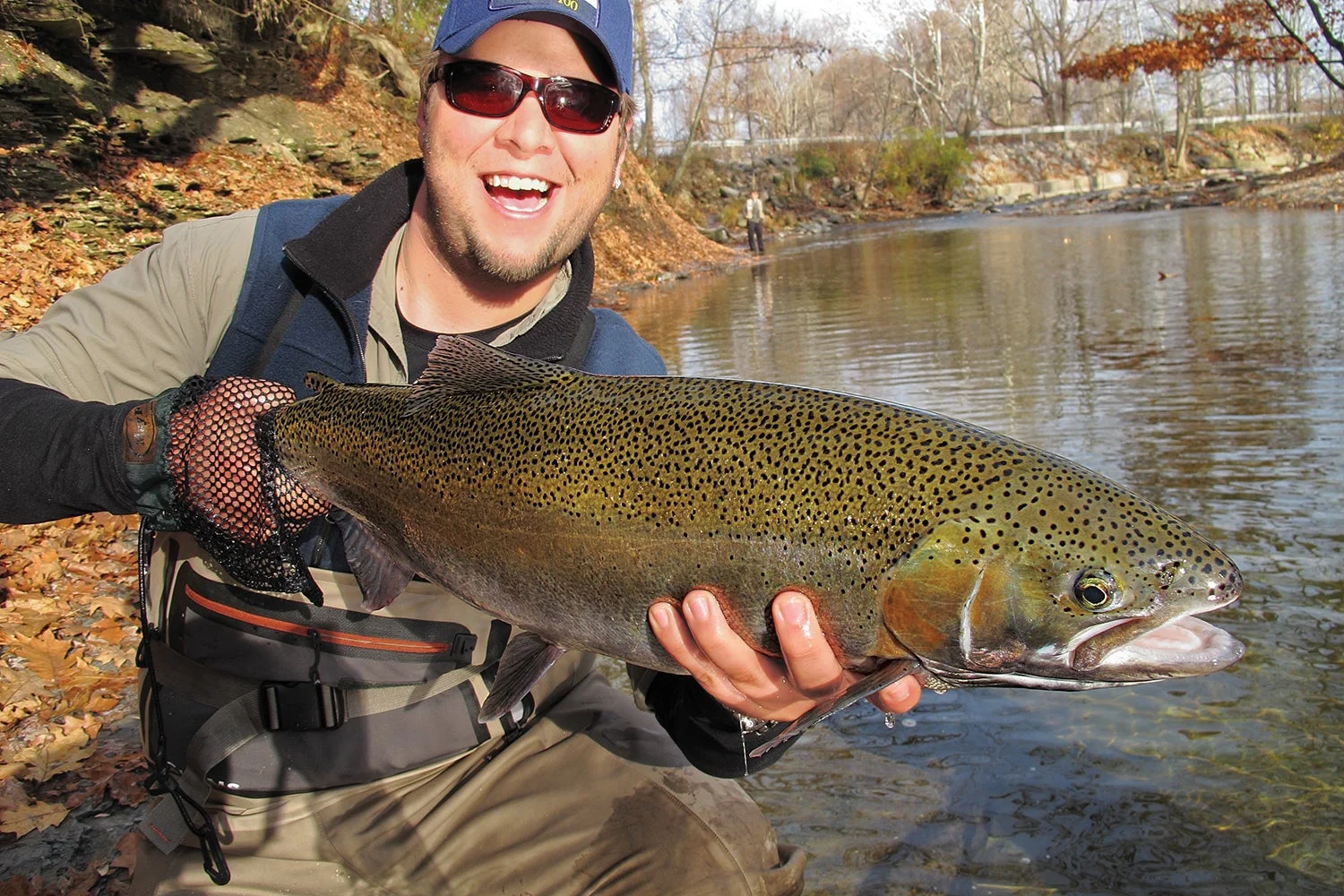 Smiling angler holds up large steelhead