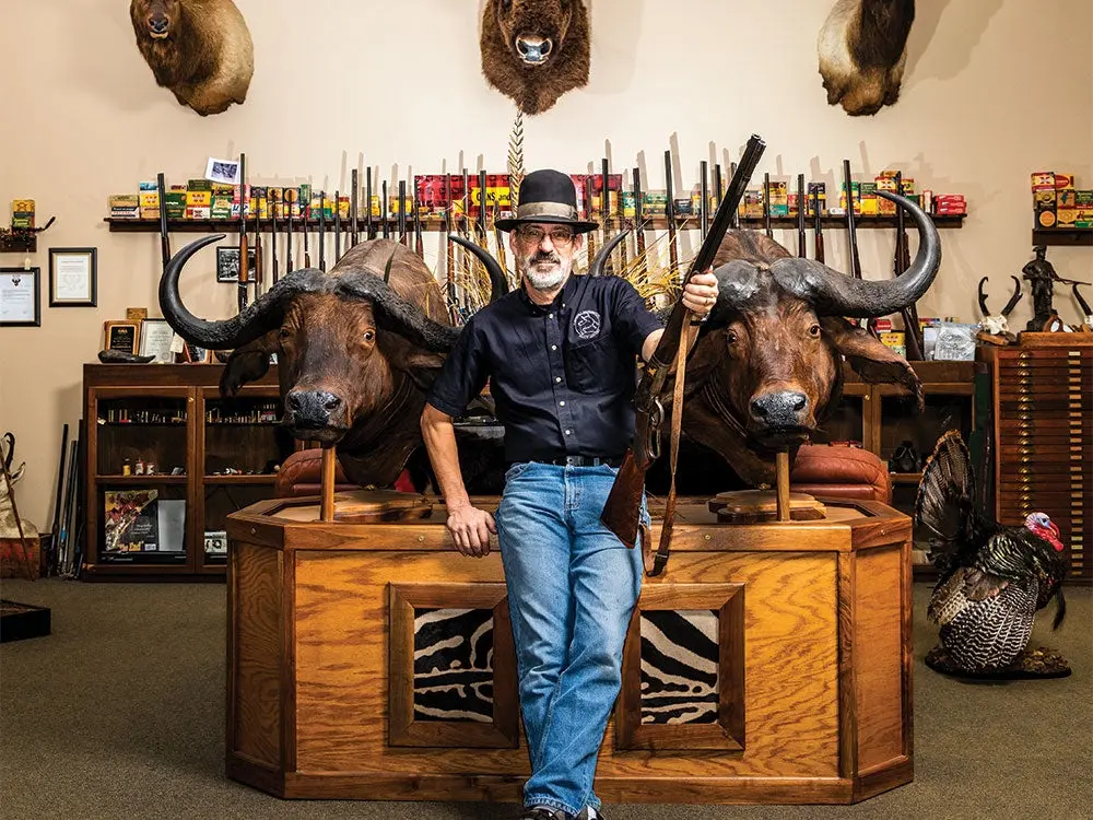 Doug Turnbull standing in from of antique guns and trophies