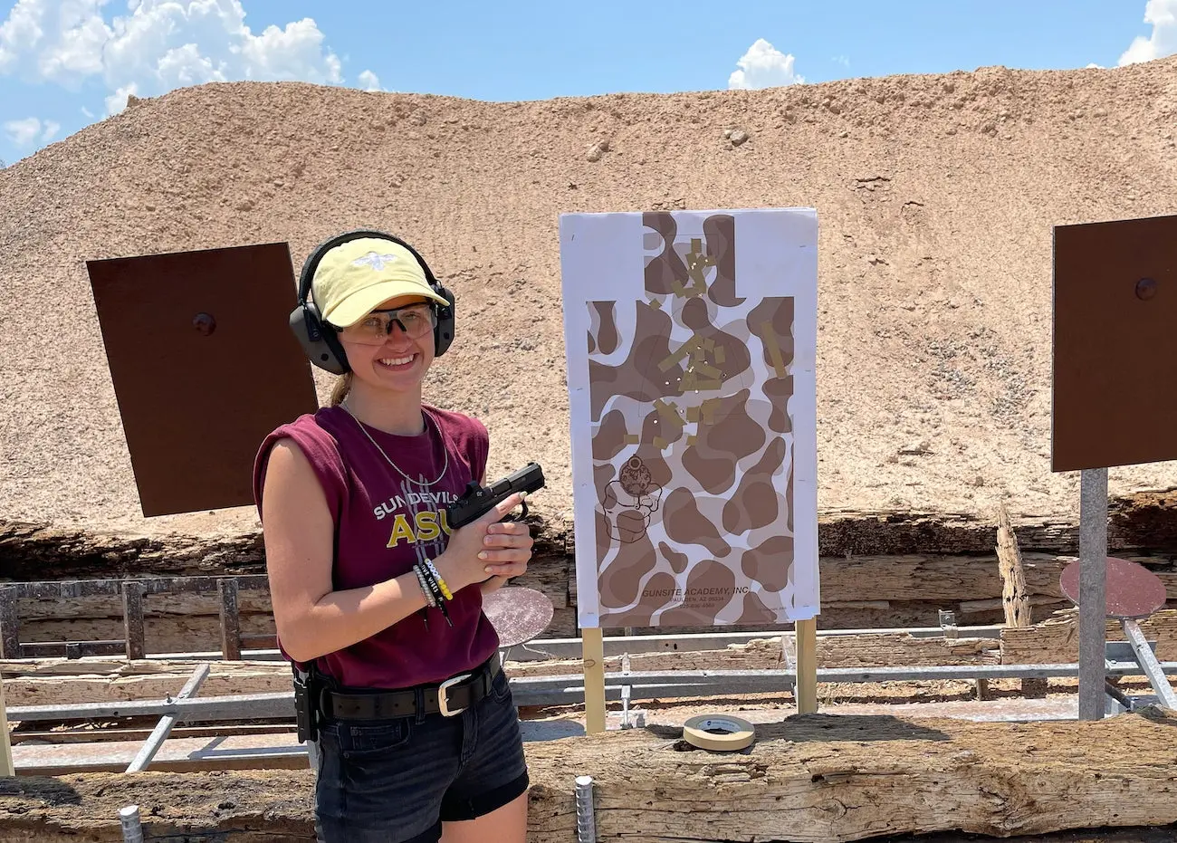 Girl next to target holding a handgun.