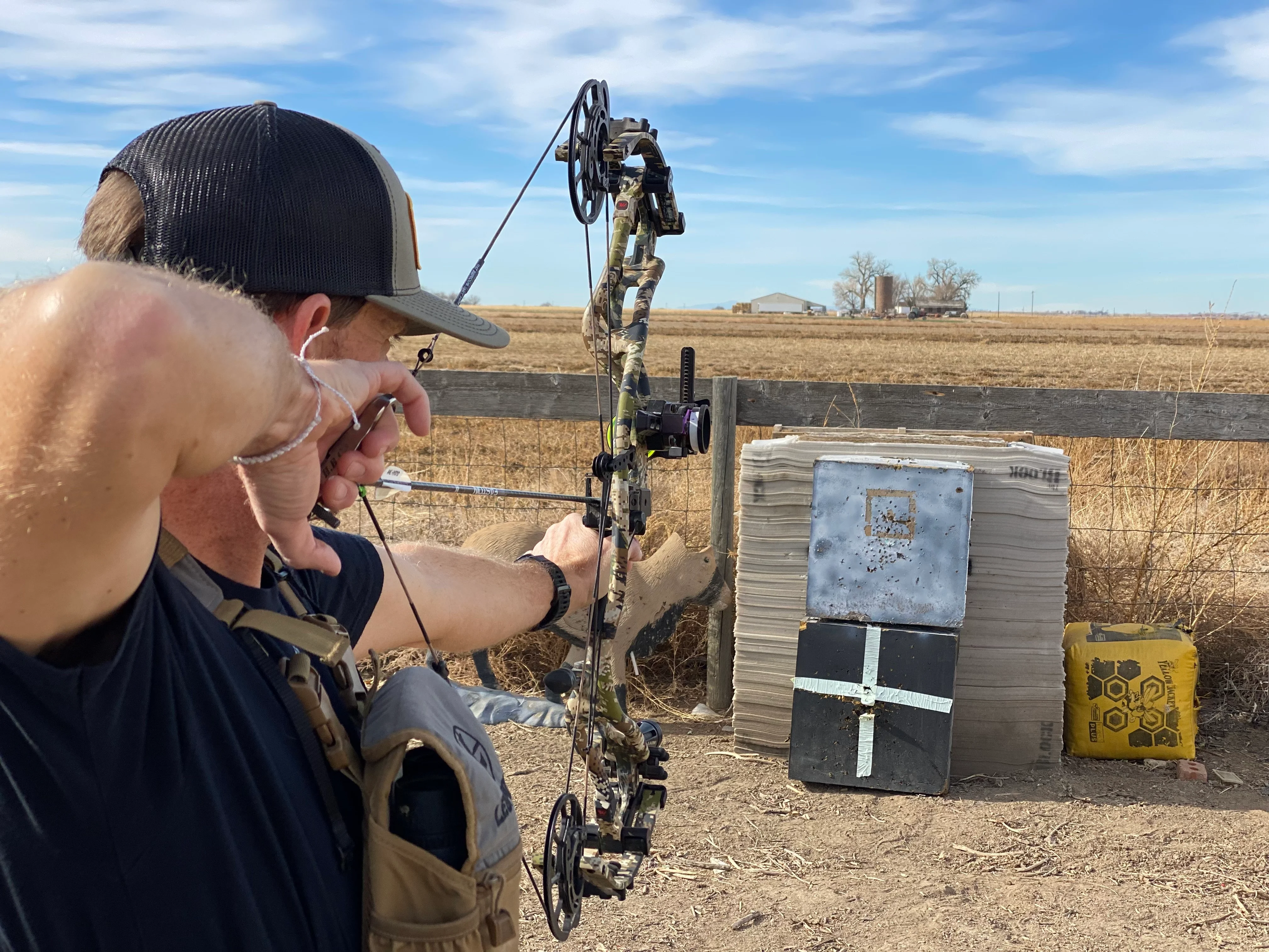An archery shoots a bow into a target set up for walk-back tuning.