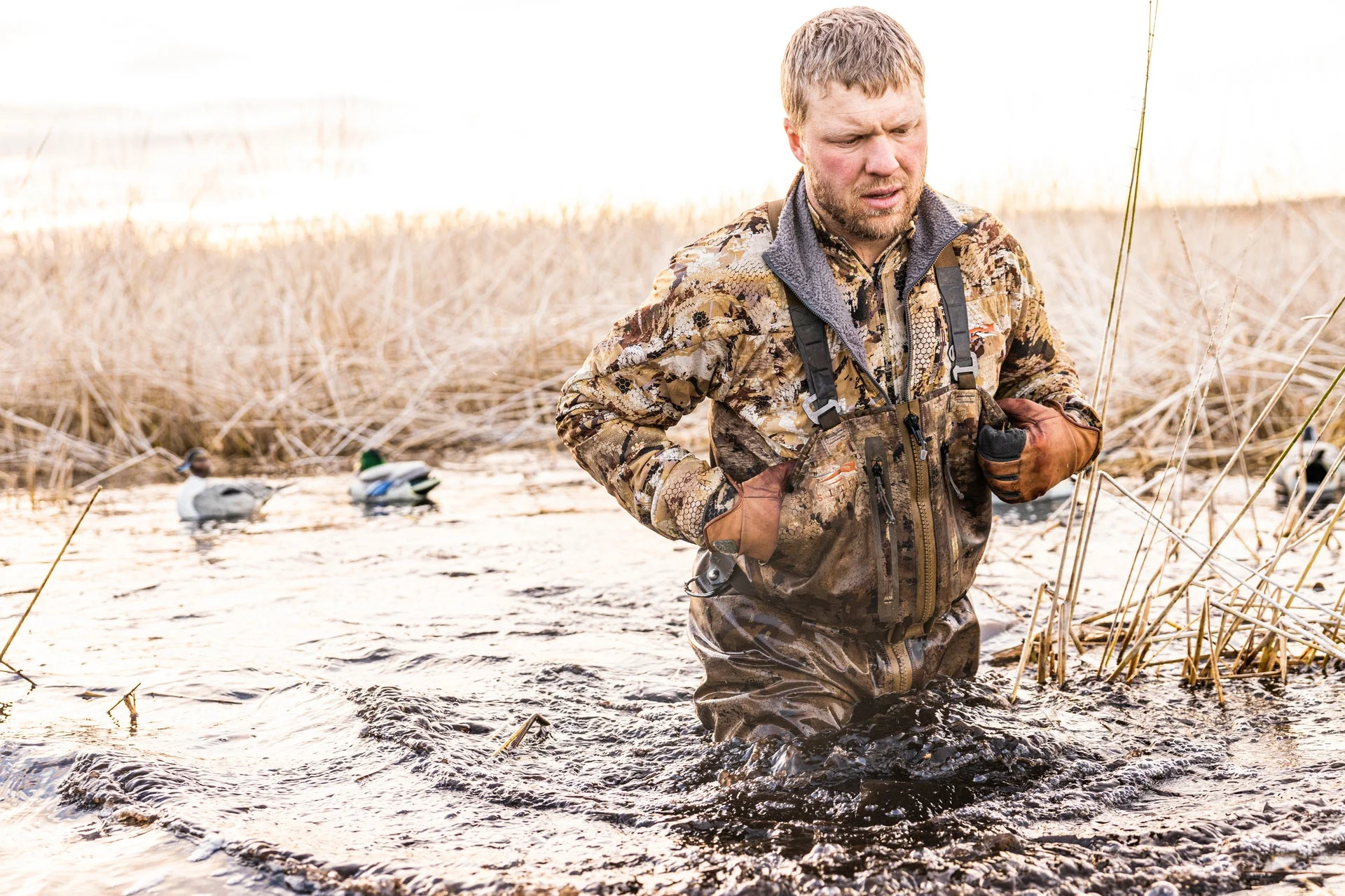 duck hunter wading in water with decoy in the background