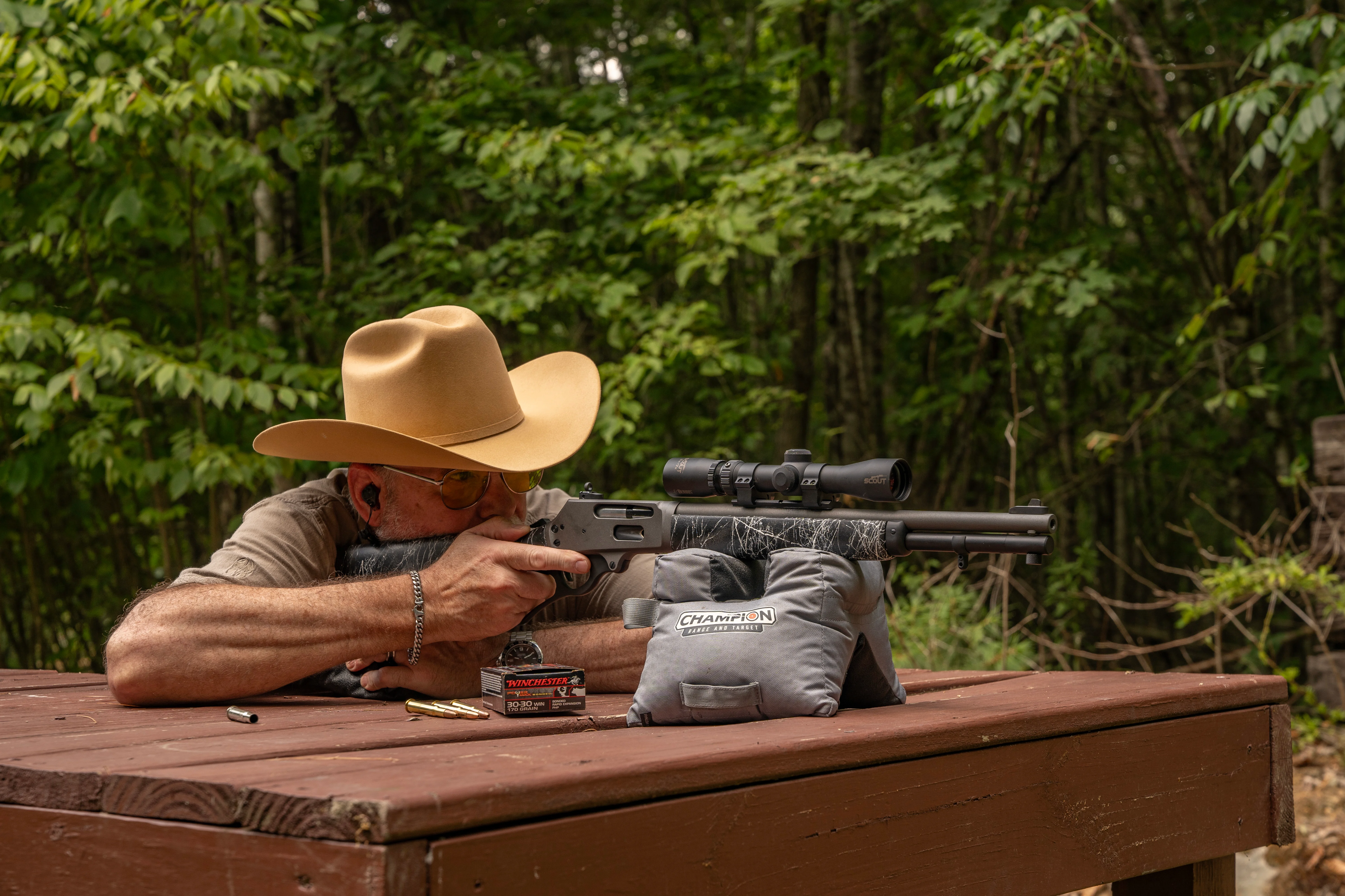 A shooter test fires a Dove Custom Appalachian Scout rifle off sandbags on a bench rest.