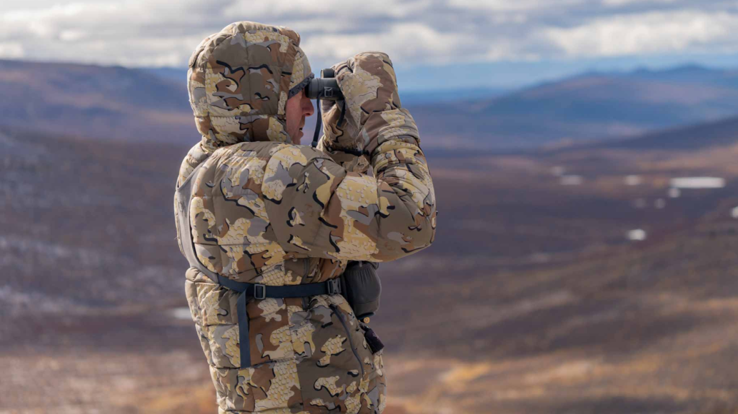 Hunter wearing KUIU Super Pro Down Hunting Jacket looking through binoculars