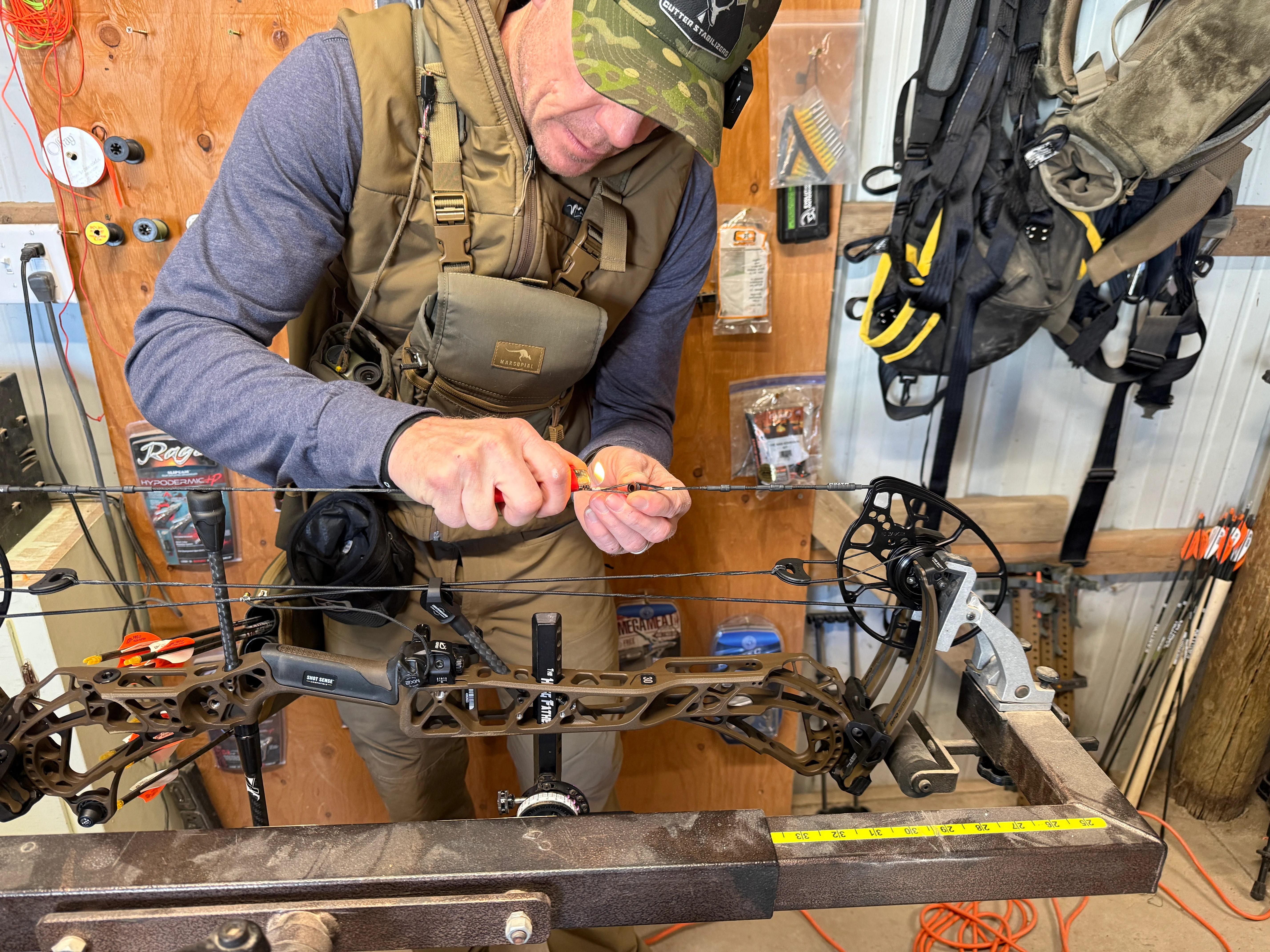 A man uses a lighter to serve in a peep sight on the new Mathews ARC 30 compound bow.