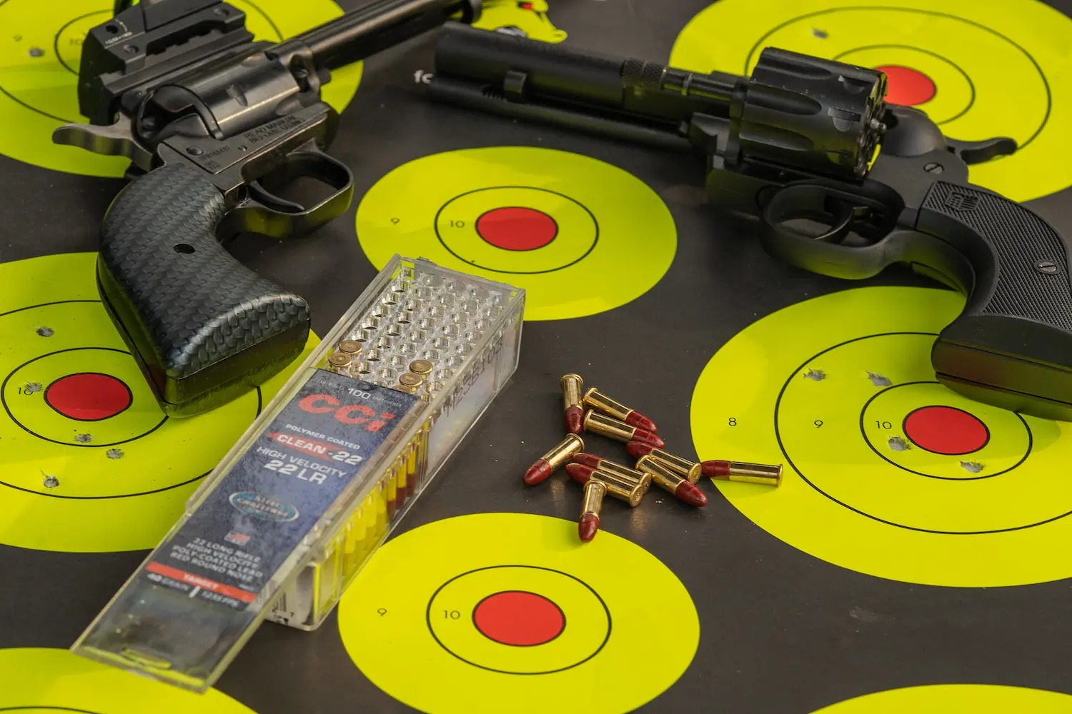 Two rimfire revolvers on a target with ammo.