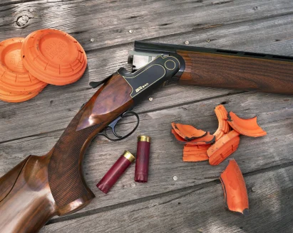 Rizzini BR240 Cole Special Sporting shotgun on wood surface with clay targets. 