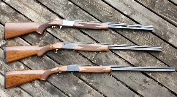 Three shotguns on a wooden deck.