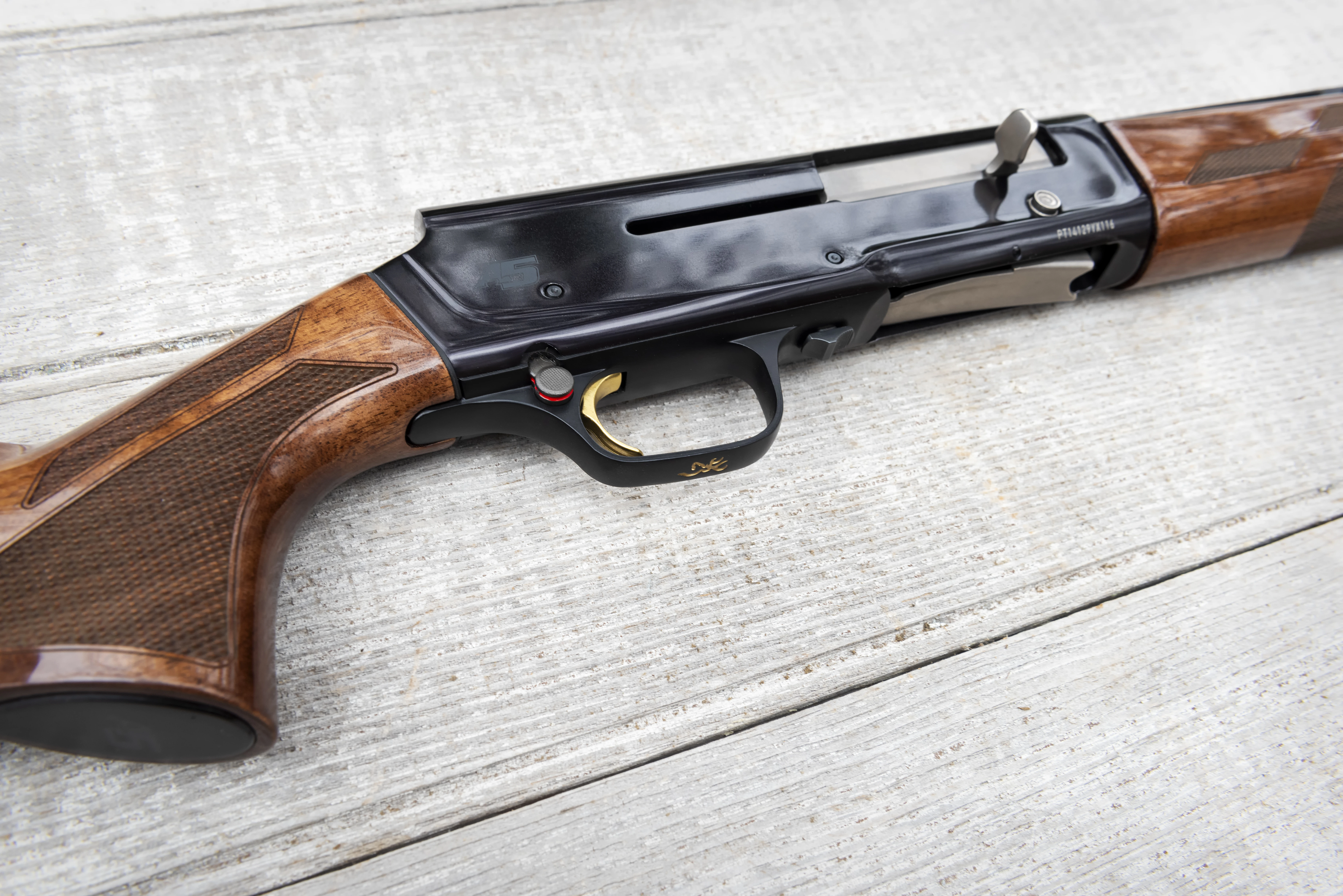 Close-up photo of Browning A5 Hunter 20-gauge shotgun on a wood background. 