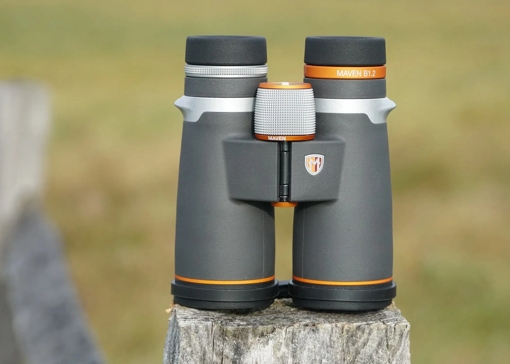 Maven B1.2 10x42 binocular sitting on a fence post with field in background.