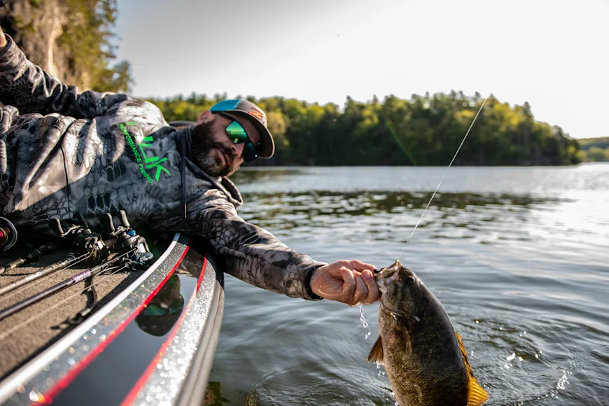 Angler holding smallmouth bass over the side of the boat