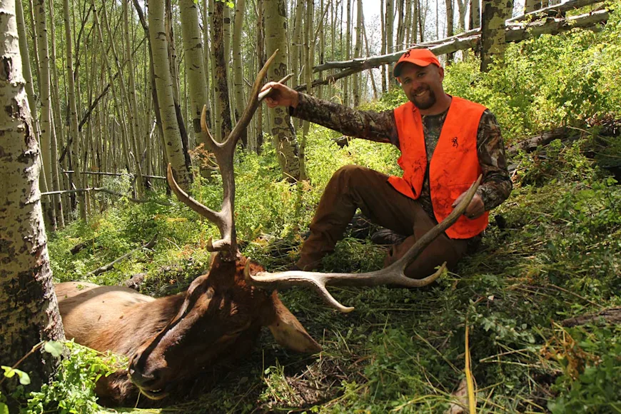A hunter poses with a bull elk taken with a muzzleloader.