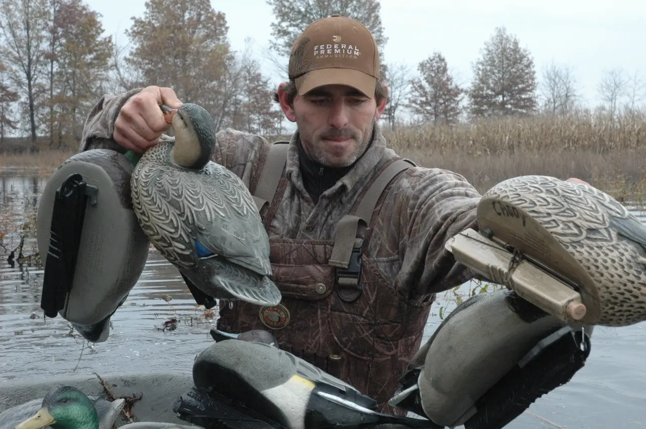 Duck hunter standing in water holding decoys