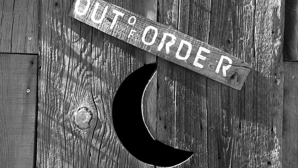 An outhouse door with a crescent moon and a sign that say out of order