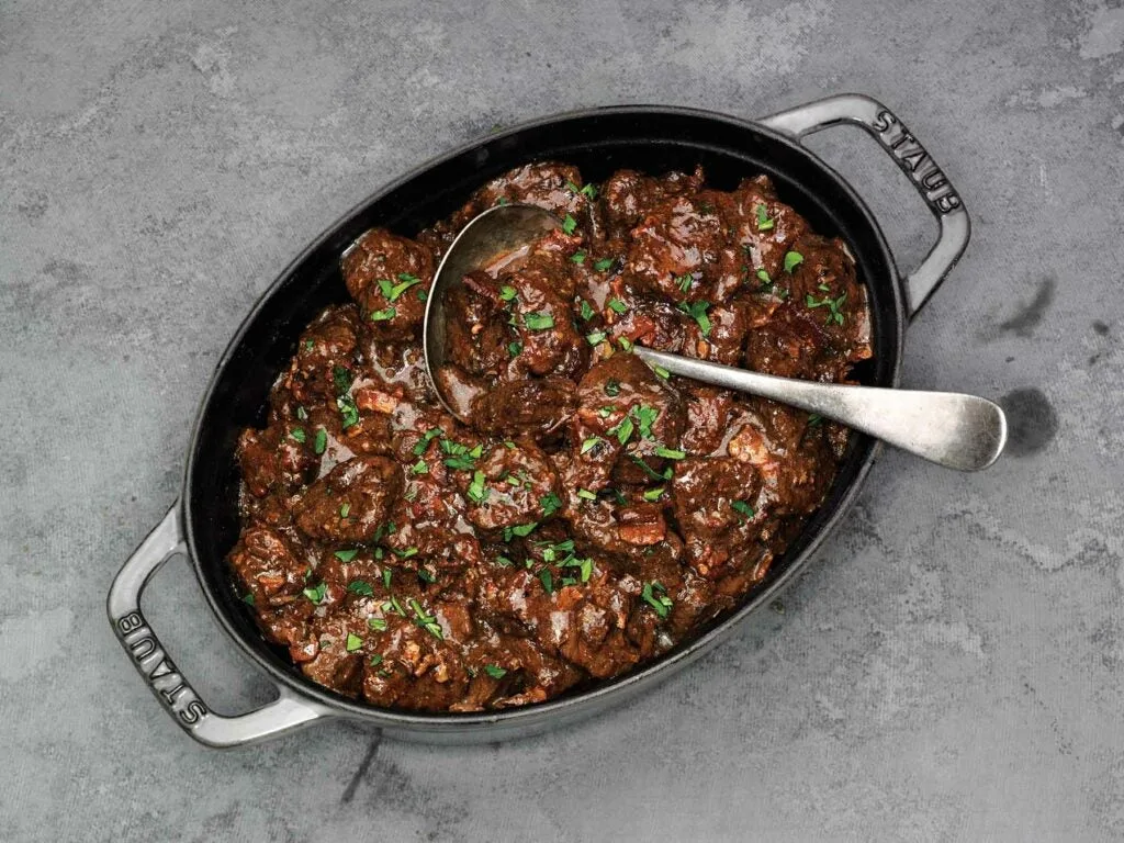 A pot of carbonnade, a venison stew recipe, resting on a granite countertop. 