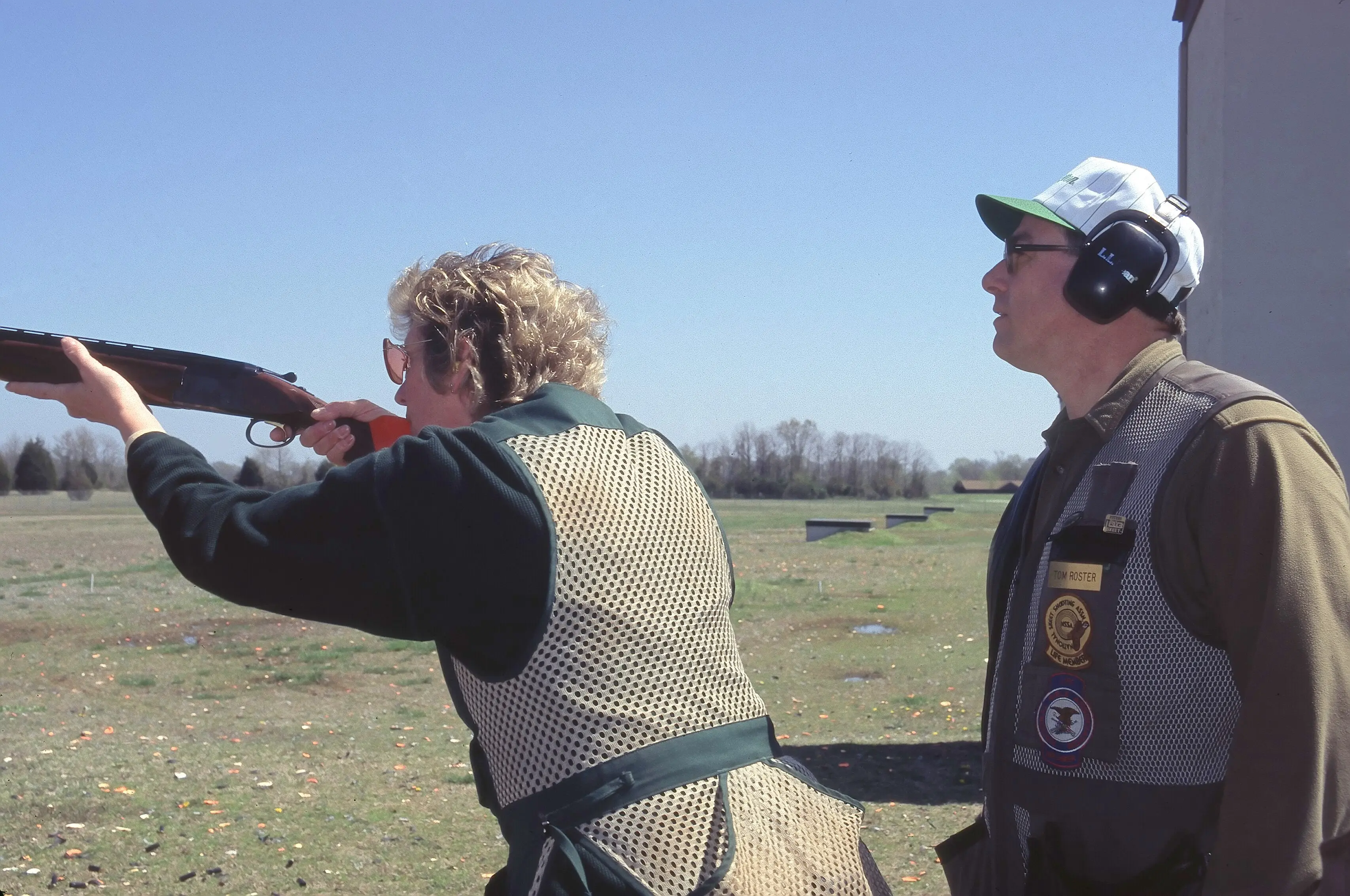 Shotgun instructor next to person shooting at a skeet range 